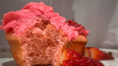 A deliciously moist strawberry cupcake with a few strawberries as garnish